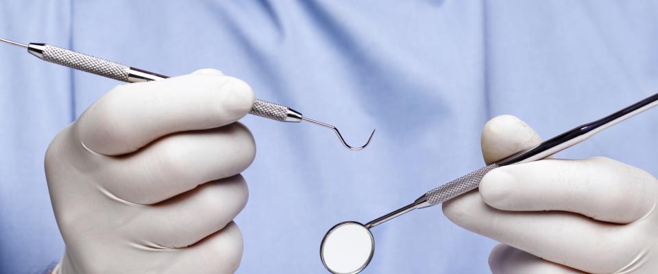 gloved hands holding dental tools