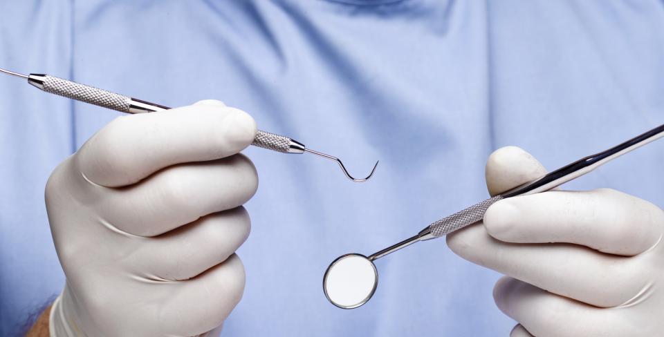gloved hands holding dental tools